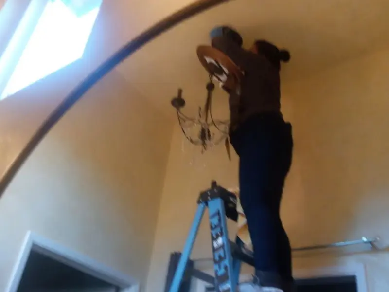 Electrician installing a chandelier in a Fenton residence